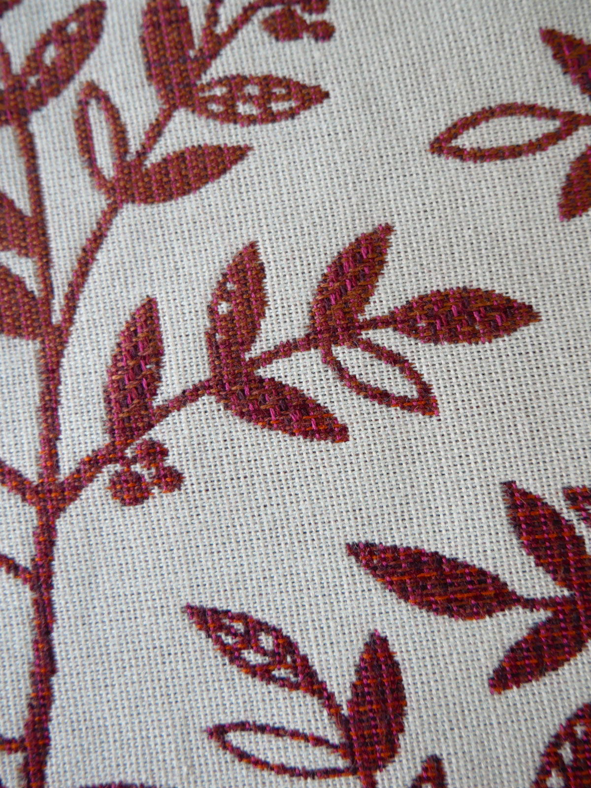 Close-up of fabric with Burgundy purple leaf pattern on a beige background
