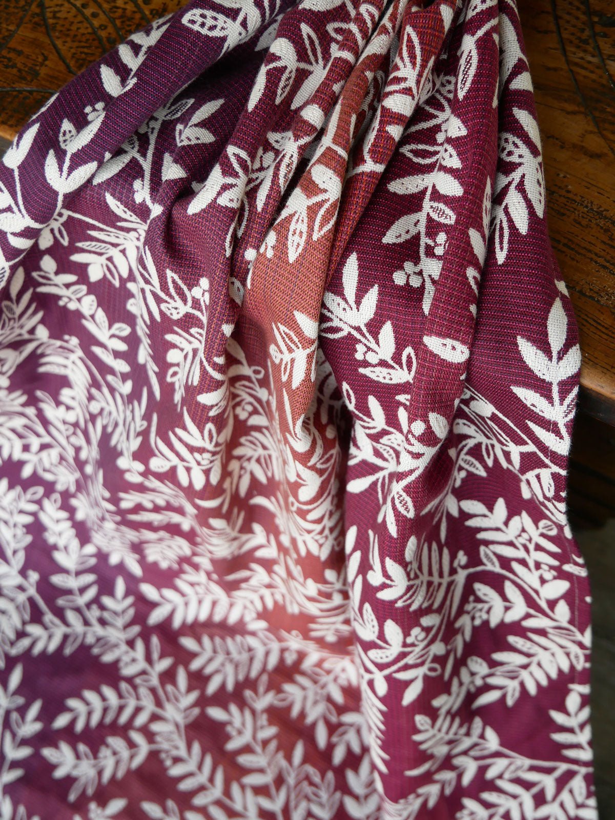 Folded fabric with white leaf pattern on a purple and red background