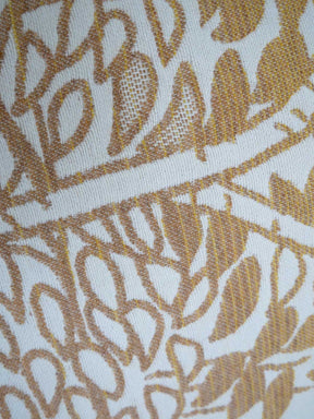 Close-up of a fabric with a gold leaf pattern on a white background