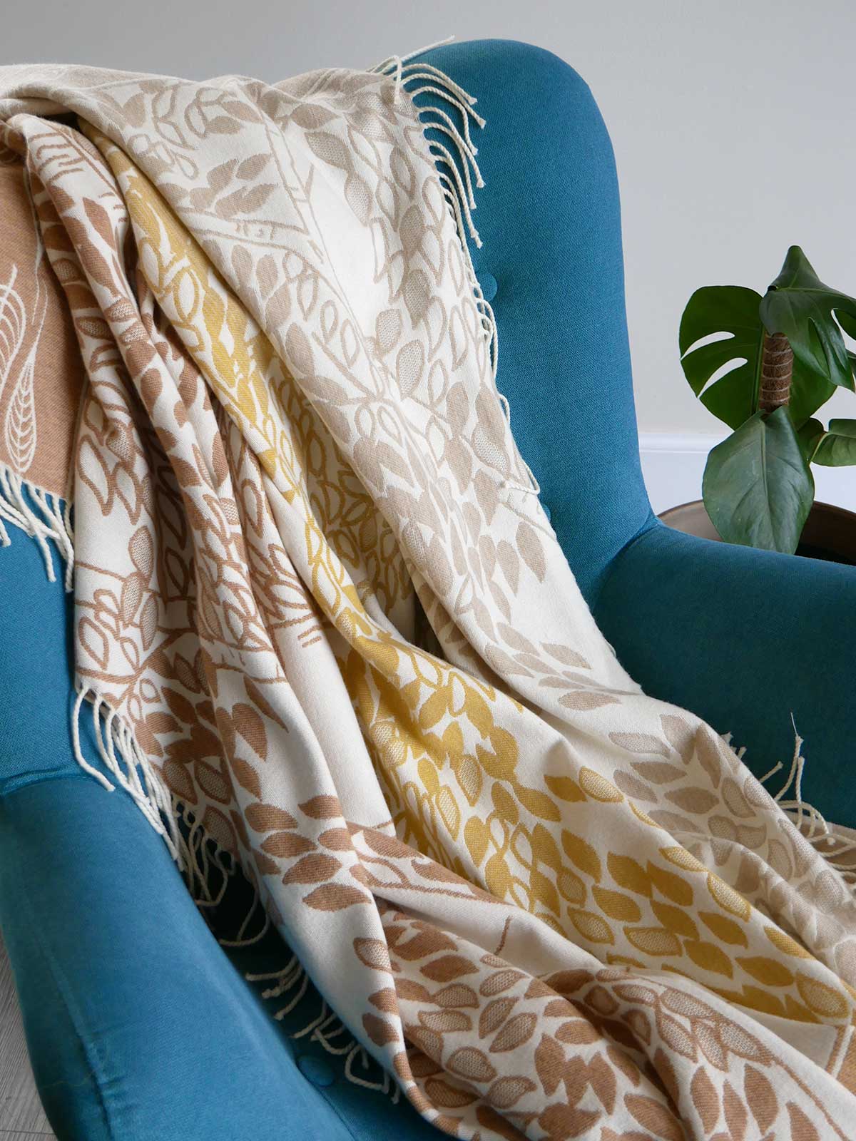 Patterned blanket draped over a blue chair with a plant in the background
