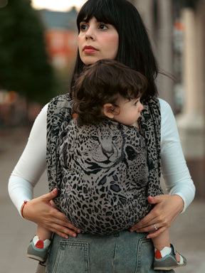 Woman carrying a child in a leopard print Prowl Savannah Baby Wrap.