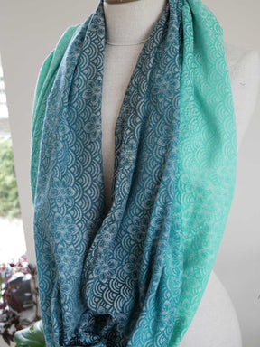 Teal patterned infinity loop on a mannequin with a blurred indoor background