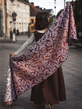Woman holding a large floral-patterned woven wrap on a street