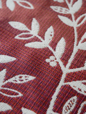 Close-up of a fabric with white leaf patterns on a burgundy background