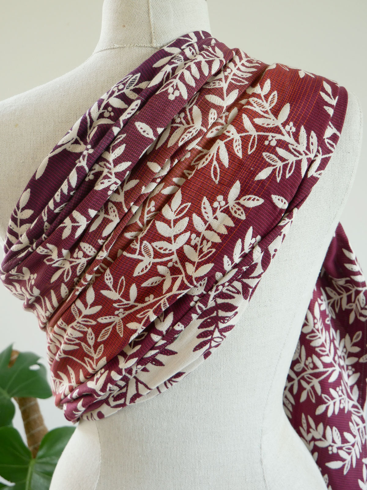 Patterned ring sling on a mannequin with a blurred plant background